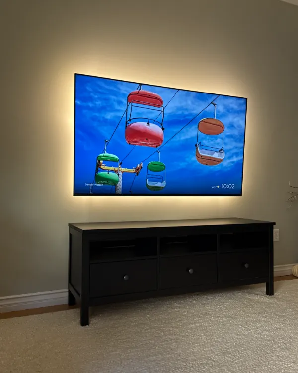 TV with a warm backlight over a long black console, no cables in sight