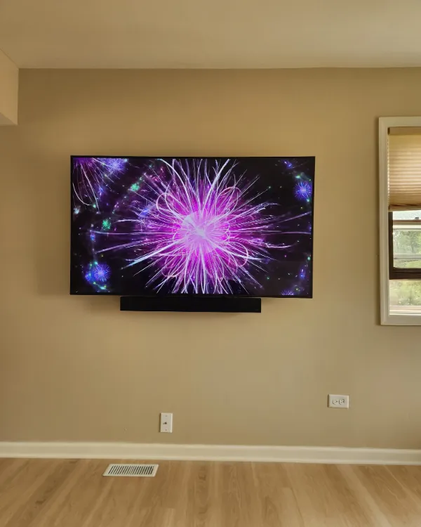 TV with a soundbar below it on a beige wall, no visible cables